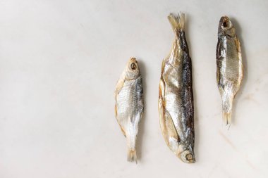 Kurutulmuş balık veya stockfish beyaz mermer zemin üzerinde. Düz lay, uzay