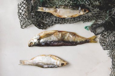 Balık ya da balık ağlarına üzerinde stockfish beyaz mermer arka plan üzerinde kurumuş. Düz lay, uzay