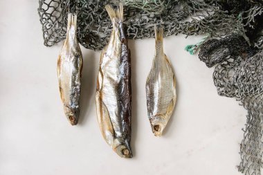 Balık ya da balık ağlarına üzerinde stockfish beyaz mermer arka plan üzerinde kurumuş. Düz lay, uzay