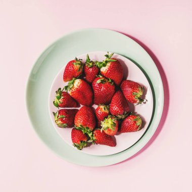 Pembe pastel pin-up arka plan üzerinde turkuaz plaka üzerinde taze çilek. Uzay kopyalayın. Üstten görünüm. Kare görüntü