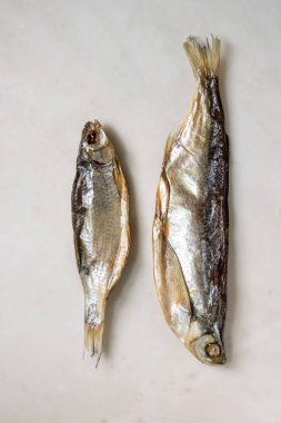 Kurutulmuş balık veya stockfish beyaz mermer zemin üzerinde. Düz lay, uzay