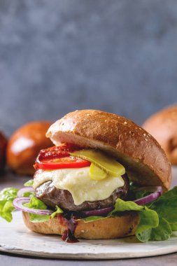 Buğday topuz sığır ve Dana pirzola, eritilmiş peynir ve beyaz seramik tahta sebze ile ev yapımı klasik Burger gri mavi masa üzerinde yakın çekim. Kopya alanı
