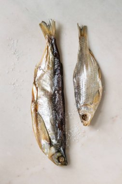 Kurutulmuş balık veya stockfish beyaz mermer zemin üzerinde. Düz lay, uzay