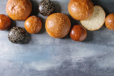 Ev yapımı geleneksel ve siyah mürekkep balığı mürekkep farklı boyut burger buns susam ile çeşitli bütün tohum ve mavi doku arka plan üzerinde dilimlenmiş. Yat, alanı Kopyala