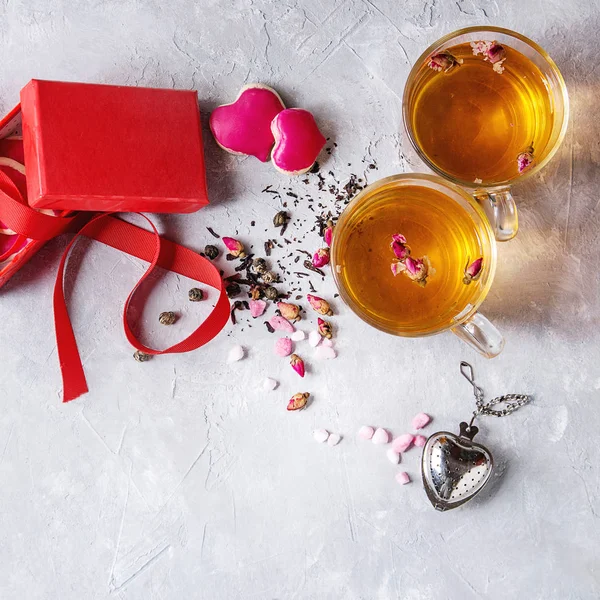 爱情人节贺卡与两杯热茶 玫瑰花蕾 心形饼干作为礼物 粉红色糖 茶过滤器 红色丝带 灰色背景 顶视图 正方形图像 — 图库照片