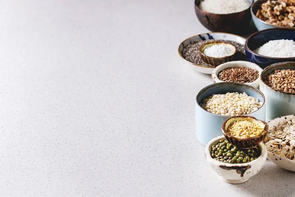 各種生調理穀物 Superfood 穀物チア種子 リネン クルミ タピオカ オートミール ココナッツ 灰色の背景の上のセラミック ボールでご飯 — ストック写真