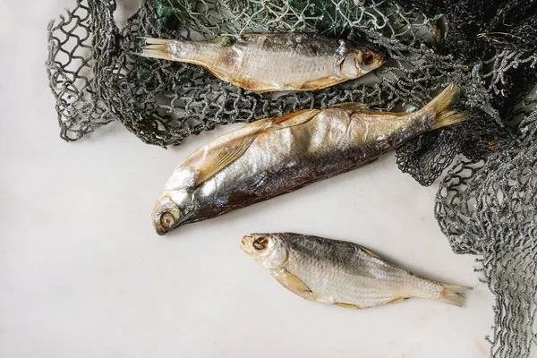 Trockenfisch Oder Stockfisch Auf Fischernetzen Vor Weißem Marmorhintergrund Flache Lage — Stockfoto