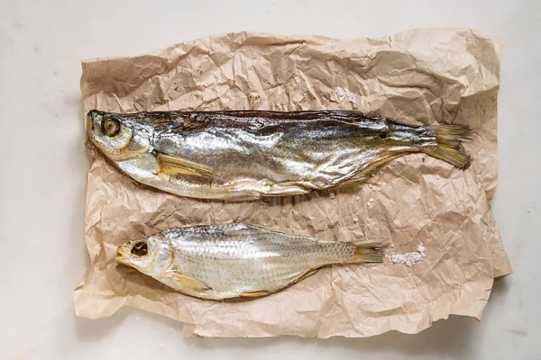 Getrockneter Fisch Oder Stockfisch Auf Zerknülltem Papier Über Weißem Marmorhintergrund — Stockfoto