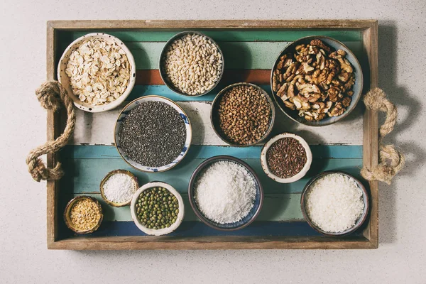 各種生調理穀物 Superfood 穀物チア種子 クルミ タピオカ オートミール ココナッツ 木製板トレイのセラミック ボールで米 フラットを置く — ストック写真