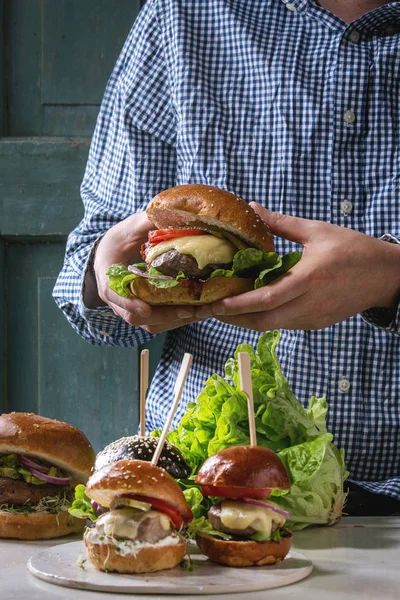 Człowiek Niebieską Koszulę Trzymając Ręce Domu Classic Burger Pszeniczne Bułeczki — Zdjęcie stockowe