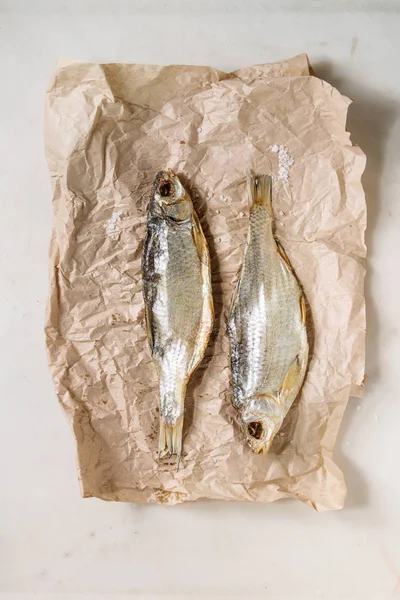 Dried fish or stockfish on crumpled paper over white marble background. Flat lay, space — Stock Image Dried Fish Stockfish Crumpled Paper White Marble Background Flat Lay Stock Picture