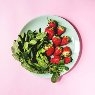 Taze çilek ve demet nane pembe pastel pin-up arka plan üzerinde turkuaz plaka üzerinde. Uzay kopyalayın. Üstten görünüm. Kare görüntü