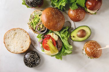 Sığır eti ve dana pirzola, portobello mantar, avokado, eritilmiş peynir ve beyaz mermer masada sebze ile buğday ve siyah çörekler ev yapımı klasik, vegan ve mini burger Çeşitleri.