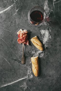 Dilimlenmiş jamon, salam, chorizo sosis ekmek ve siyah mermer zemin üzerinde kırmızı şarap ile çatal üzerinde meze et assorti. Düz lay, alan. Meze kavramı