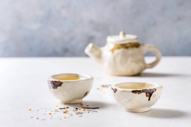 Sıcak yeşil çay iki geleneksel Çin Kil seramik Kupası ve beyaz mermer masada duran çaydanlık.