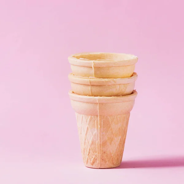 Stack of empty waffle cups for ice cream over pink pastel pin-up background. Copy space. Square image