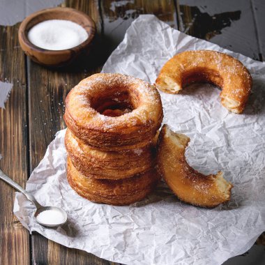 Ev yapımı puf böreği derin kızarmış çörek veya cronuts şeker buruşuk ayakta yığınındaki koyu ahşap beton masa üzerinde kağıt. Kare görüntü