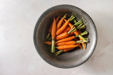 Beyaz mermer zemin üzerinde vintage metal kapta genç mini havuç. Düz lay, alan. Pişirme kavramı, gıda arka plan.