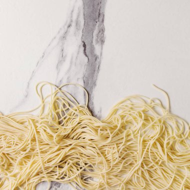 İrmik unu beyaz mermer doku arka plan üzerinde ev yapımı İtalyan pişmemiş makarna spagetti. Düz lay, alan. Kare görüntü