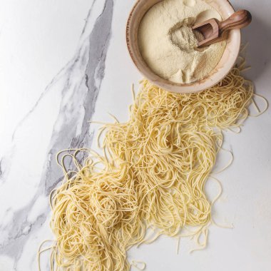 Ev yapımı İtalyan pişmemiş makarna İrmik unu beyaz mermer doku arka plan üzerinde kâse spagetti. Düz lay, alan. Kare görüntü