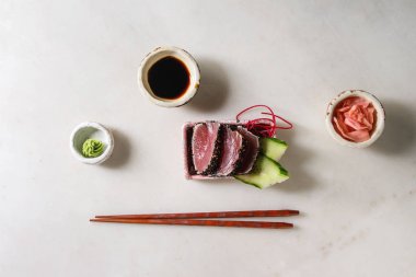 Ton balıklı Sushi sashimi pembe seramik plaka çubuklarla, hizmet içinde salatalık ile kase soya sosu ve turşu zencefil, pamuk çiçek beyaz mermer zemin üzerinde. Düz lay, alan. Japonya menü