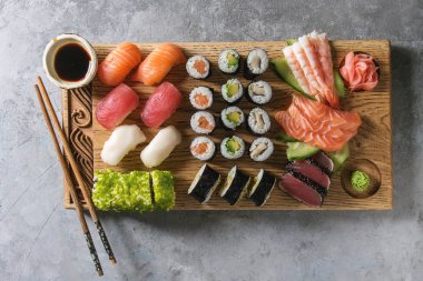 Suşi Set nigiri sashimi ve suşi rulo soya sosu ve gri beton arka plan üzerinde yemek çubukları ile ahşap hizmet gemide. Düz lay, alan. Japonya menü