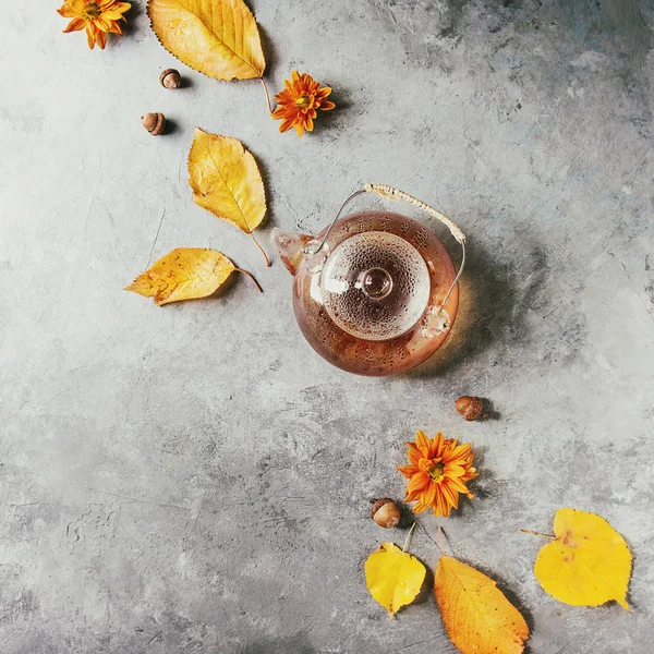 Glas Teekanne mit Herbstblättern — Stockfoto