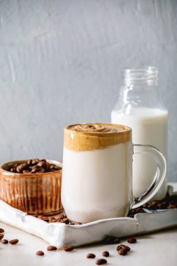 Dalgona köpüklü kahve trend Kore sütlü latte, cam bardak köpüklü seramik tepside beyaz mermer masa malzemeleri..