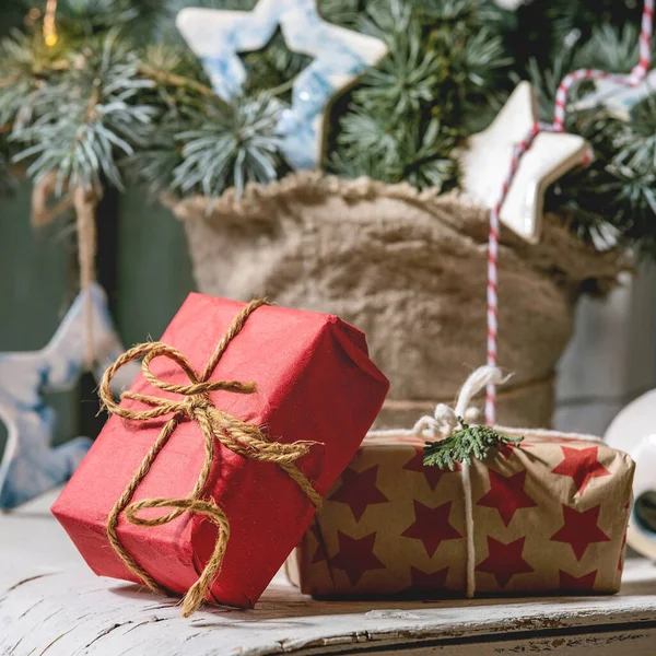 クリスマスの装飾モミの木の枝 セラミックスター 明るいガーランド 背景に木製のドアとヴィンテージの白い椅子のクラフト紙のギフトボックス クリスマスと新年のインテリア — ストック写真