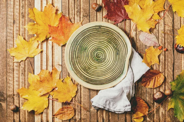 Leere Keramikteller Mit Textilserviette Auf Verschiedenen Roten Und Gelben Herbstblättern — Stockfoto