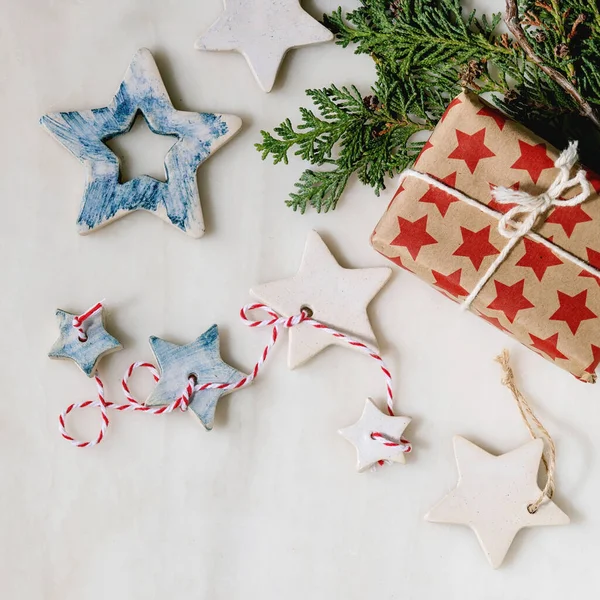 圣诞装饰陶瓷明星白色和蓝色的釉面 不同的大小 礼品盒在工艺用纸 绿色枝条在白色大理石背景之上 圣诞和新年贺卡 平坦的地方 — 图库照片