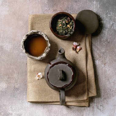 Wabi sabi Japon tarzı koyu kil bardaklar ve bez peçetede çaydanlık içen çay. Gri desenli beton arka plan. Düz uzanış, boşluk