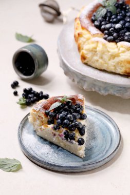 Bir parça ev yapımı yabanmersini fırında yumuşak cheesecake San Sebastian seramik tabakta, taze yabanmersinleri ile süslenmiş, krema şekeri ve beyaz desenli arkaplanda nane şekeri..