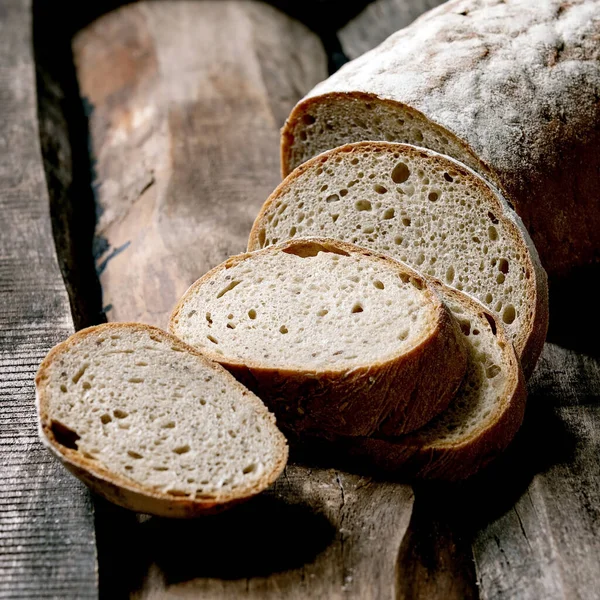 Eski ahşap zemin üzerinde dilimlenmiş tahıllı çavdar-buğday organik ekmek..