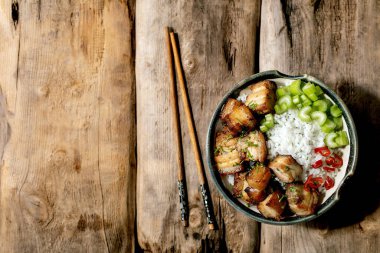 Kızarmış domuz eti kasesinde pilav, kereviz, biber ve eski ahşap arka planda çubuklu taze soğan. Düz yat, boşluğu kopyala