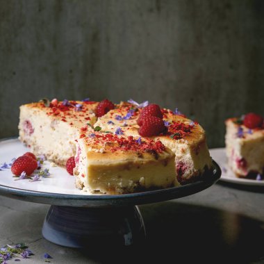 Ev yapımı ahududu fırınlanmış cheesecake taze ahududu ve gri masada nane şekeri ile süslenmiş tabakta. Düz uzanış, boşluk