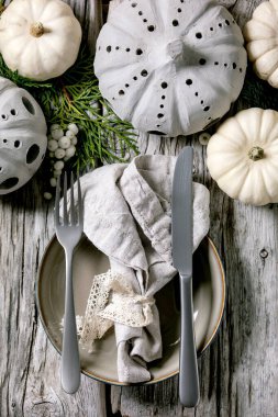 Dekoratif balkabakları, el işi balkabakları, thuja dalları, bez peçeteli boş tabaklar, eski ahşap masanın üzerine çatal bıçak takımı. Düz uzanış, boşluk