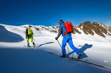 Two alpinist skiers during a ski mountaineering trip. clipart