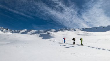 Three friends during a ski mountaineering trip on the trail. clipart