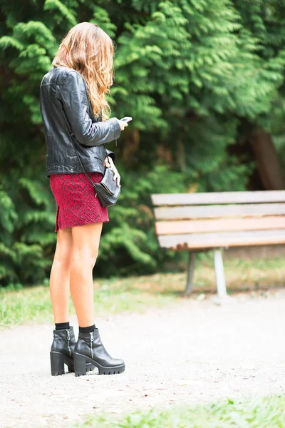 Smartphone vasıl bakmak için genç kadın durur — Stok fotoğraf