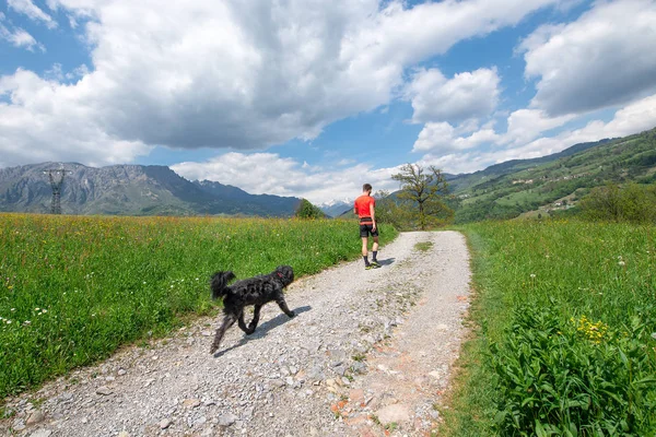 Man tijdens het lopen in de bergen met zijn hond die hem volgt — Stockfoto