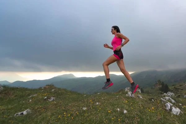 O rasto corre nas colinas. Uma mulher atleta — Fotografia de Stock