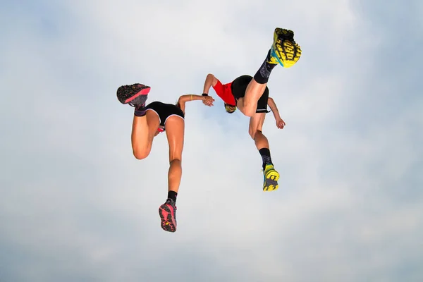 Пара спортсменів роблять стрибок у небі вручну — стокове фото
