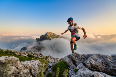 Man ultramarathon runner in the mountains he trains at sunset clipart