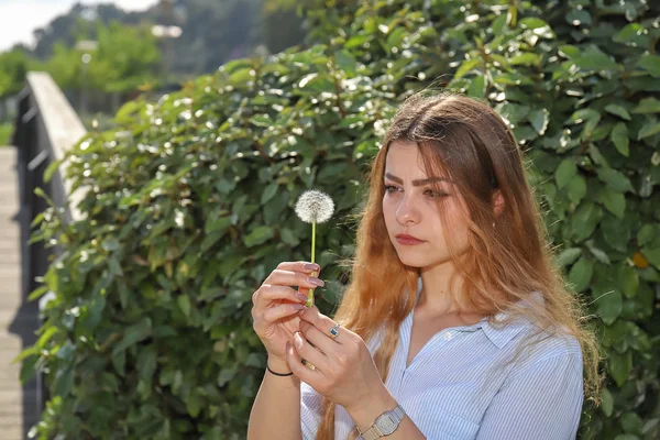 posa che contempla un fiore soffione içinde giovane ragazza