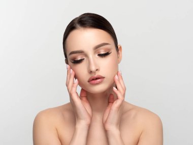 Genç güzel bir kadın yüzüne dokunuyor.