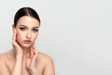 Genç güzel bir kadın yüzüne dokunuyor.