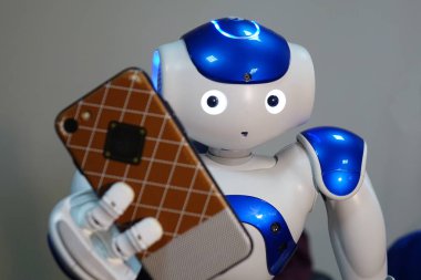 Robot telefon elinde tutuyor. Bir insan yüzü ve insansı vücut ile küçük bir robot.