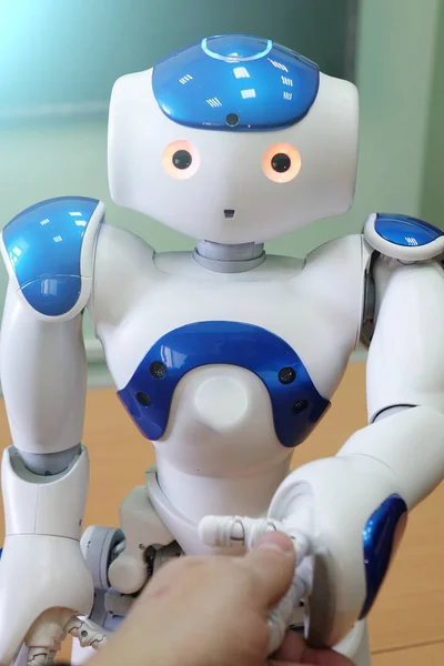 En liten robot med ett mänskligt ansikte och en humanoid kropp. Blå-vita robot. — Stockfoto