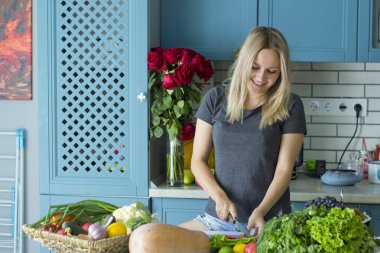 Kız mutfakta sebze ile sağlıklı yiyecek hazırlanıyor. Vejetaryen mutfağı. Onun yirmili genç bir beyaz. Sağlıklı beslenme kavramı.